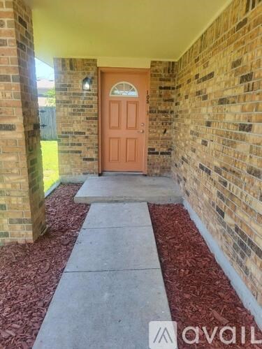 A red door is at the end of a brick wall.
