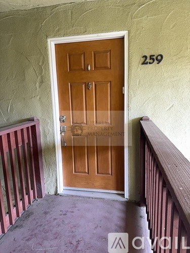 A brown door with a glass window is in front of a wall with the number 259 on it.