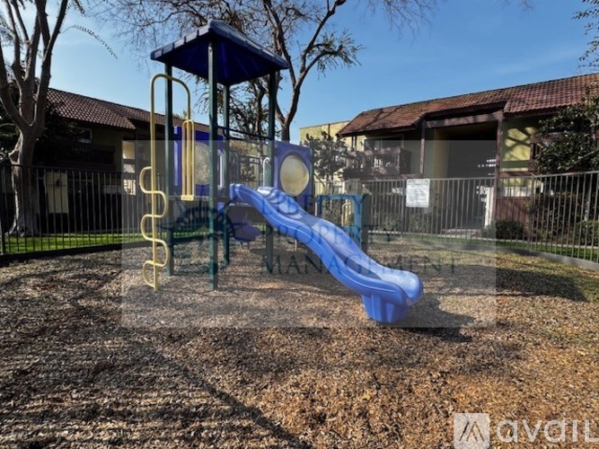 A playground with a blue slide and a yellow climbing frame.