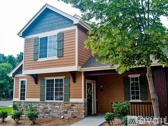 A house with a brown and tan exterior and a stone wall.