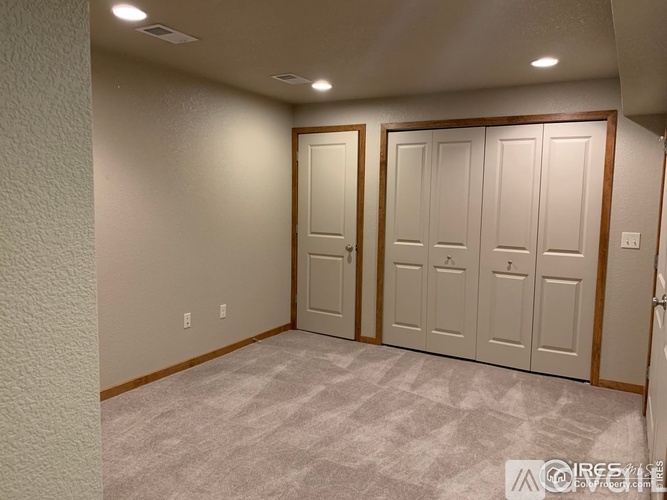 A room with a carpeted floor and three doors.