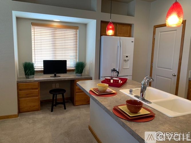 A kitchen with a desk and a computer.