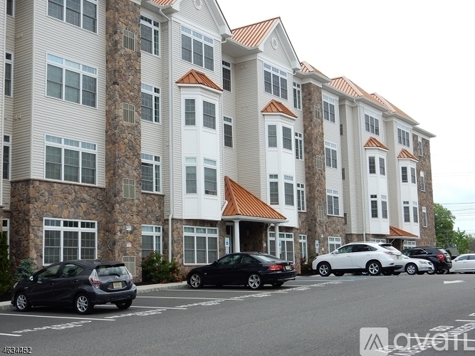 A row of apartment buildings with cars parked in front.