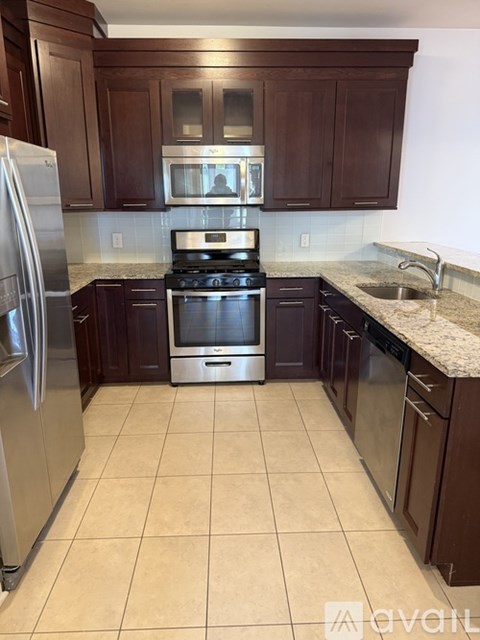 A kitchen with brown cabinets and a stainless steel refrigerator.
