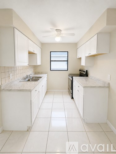 A kitchen with white cabinets and a marble countertop.