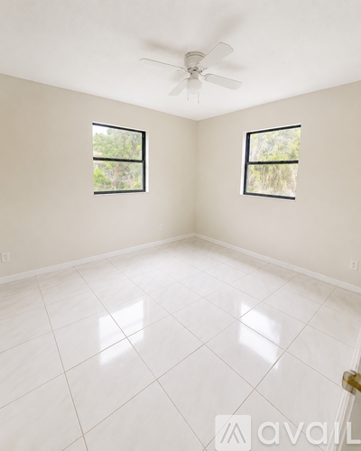 A room with a ceiling fan and two windows.