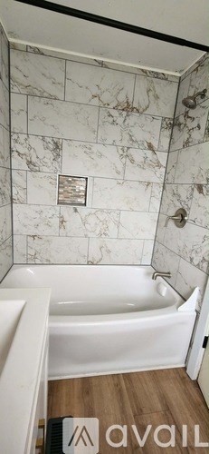 A bathroom with a marble wall and a white bathtub.