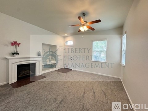 A living room with a fireplace and a ceiling fan.