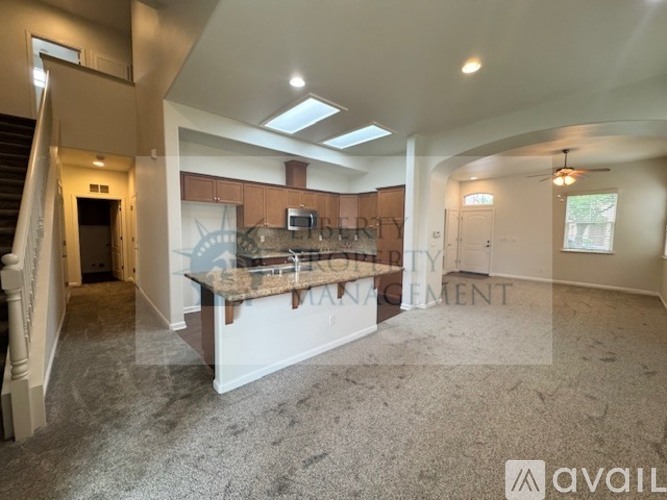 A spacious living room with a kitchenette in the background.