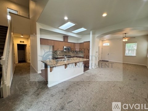 A spacious living room with a kitchenette in the background.