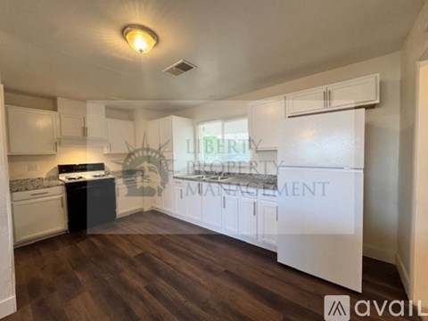 A kitchen with white cabinets and a black countertop is available for rent.