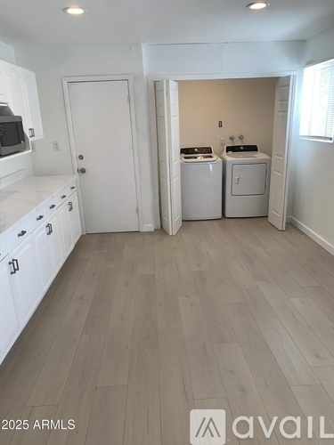 A kitchen with white cabinets and a door leading to a laundry room.