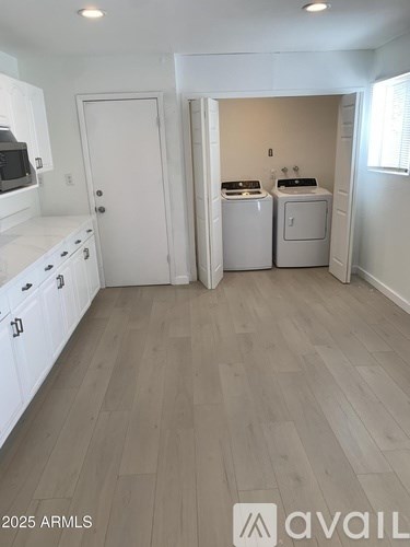 A kitchen with white cabinets and a door leading to a laundry room.