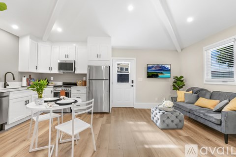 A kitchen with white cabinets and a grey couch.