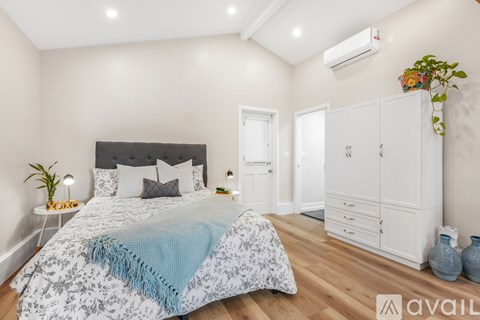 A bedroom with a large bed and a white wardrobe.