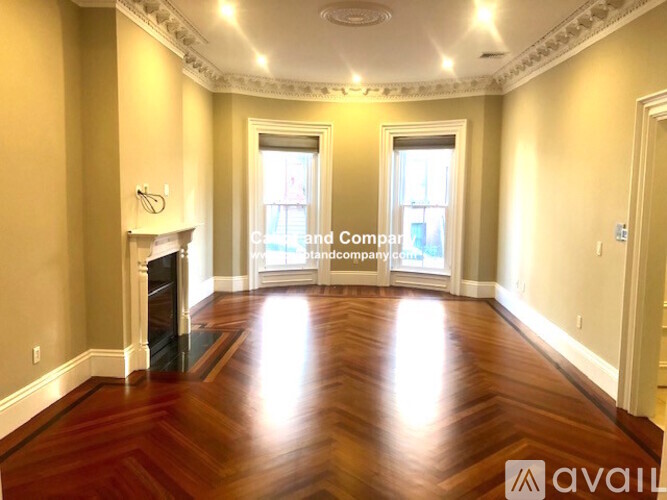 A spacious room with wood flooring and a fireplace.