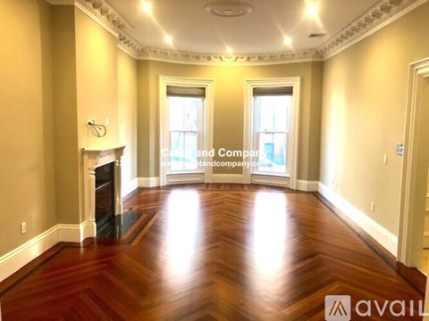A spacious room with wood flooring and a fireplace.