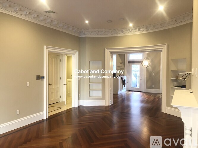 A spacious room with wooden floors and white walls.