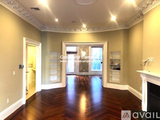 A large, empty room with wood floors and a fireplace.