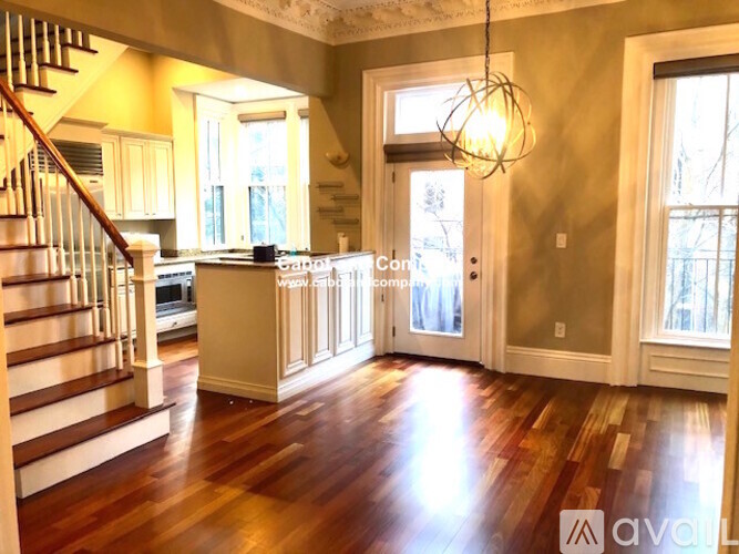 A large open living room with wood floors and a staircase.