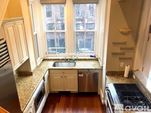 A kitchen with a sink, stove, and cabinets.