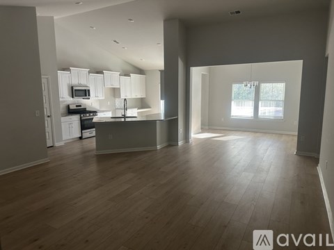 A spacious living area with a kitchen in the background.