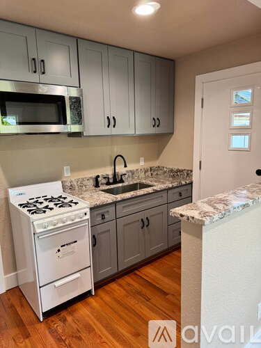 A kitchen with a white stove and grey cabinets.