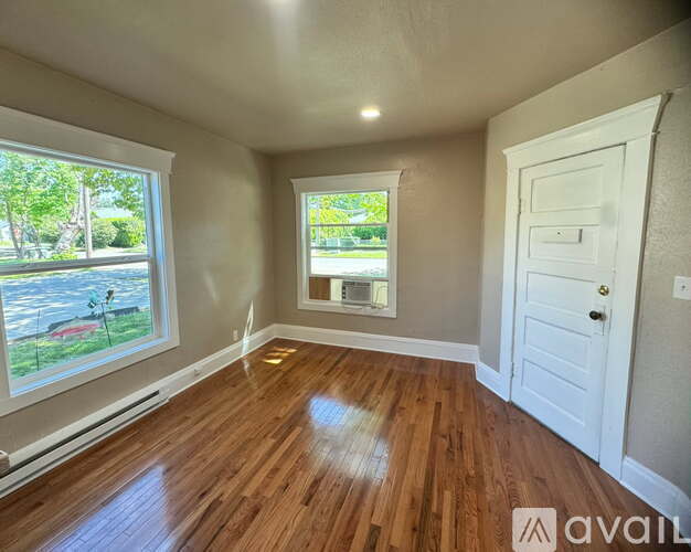 A room with wooden floors and a large window overlooking a yard.