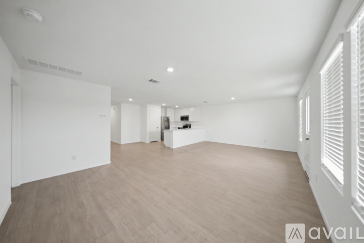 A spacious room with wooden flooring and white walls.