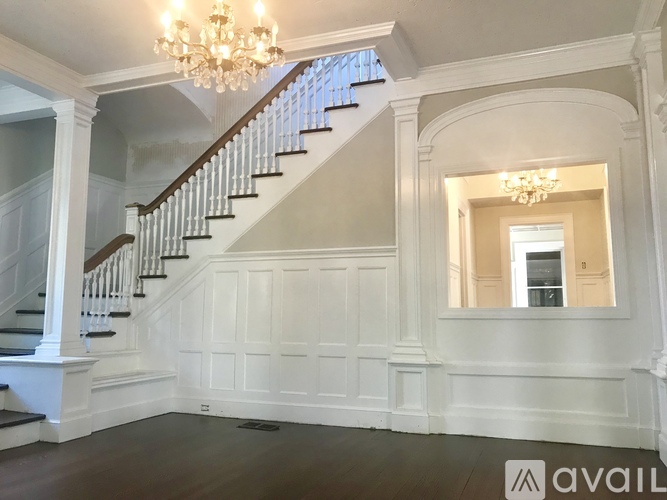 A spacious room with a staircase and a chandelier.