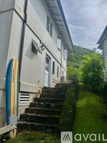 A white building with a blue surfboard leaning against it.