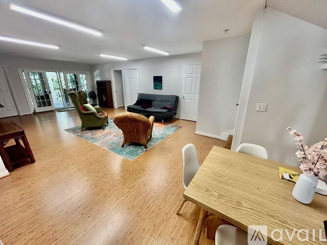A living room with a wooden floor and a dining table set up.