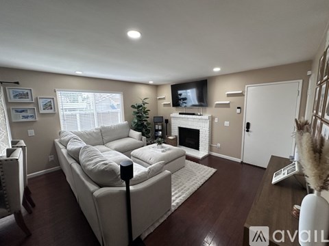 A living room with a white couch and a television mounted on the wall.