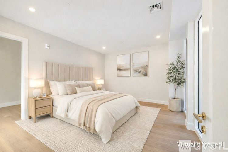 A bedroom with a large bed and a plant on the side table.