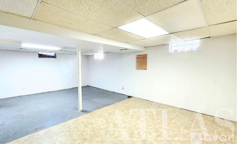 A spacious room with a white wall and a window on the right side.