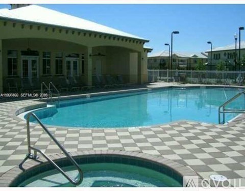 A pool with a checkered floor and a building in the background.