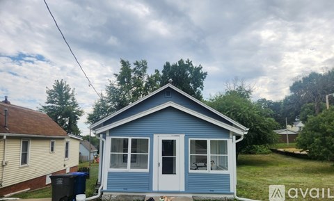 A blue house with a white door and windows is for sale.