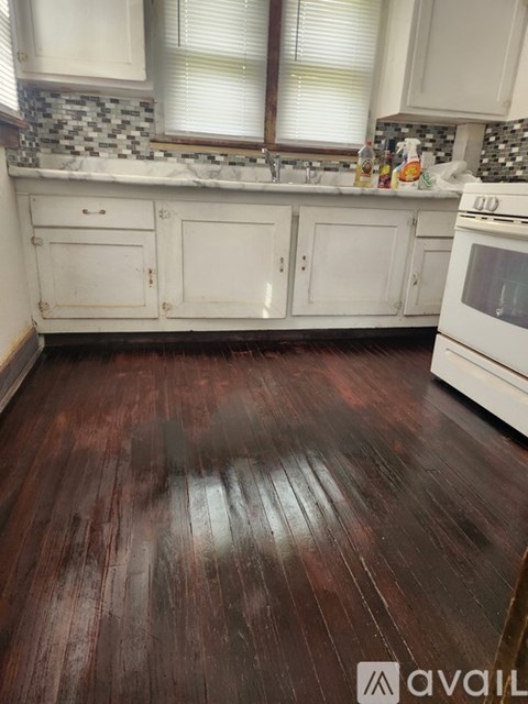 A kitchen with white cabinets and a wooden floor.