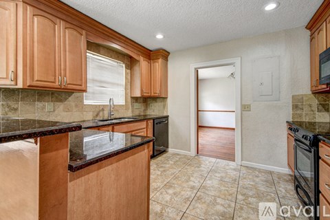 A kitchen with wooden cabinets and a black countertop.