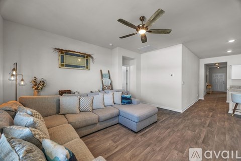A living room with a couch, a fan, and a painting on the wall.