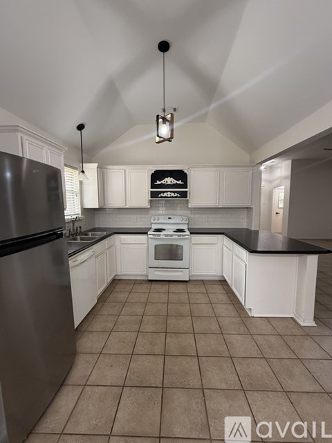 A kitchen with white cabinets and a black refrigerator.