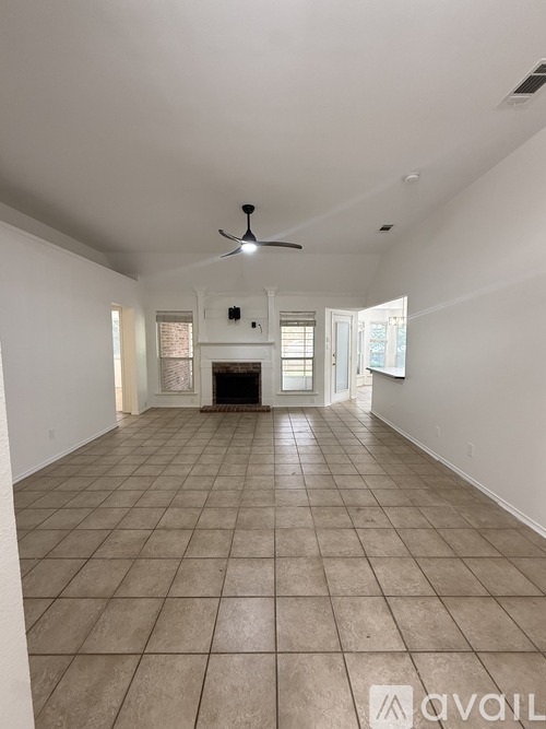 A spacious room with a fireplace and a fan on the ceiling.