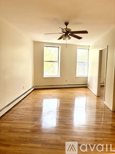 A room with a ceiling fan and wooden floors.