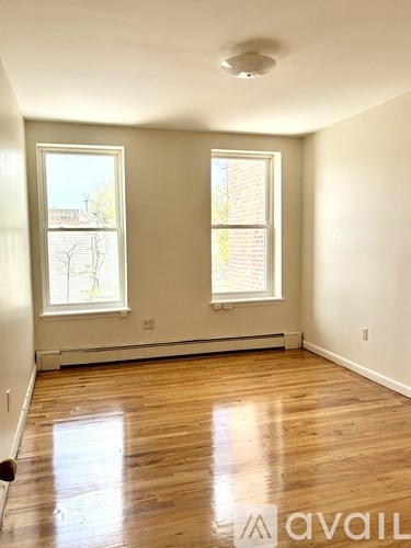 A room with wooden floors and two windows.
