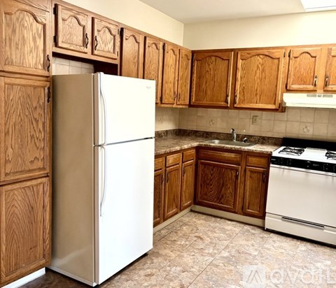 A white refrigerator in a kitchen with wooden cabinets.