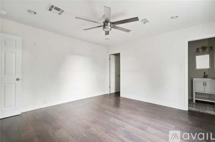 A spacious room with a ceiling fan and wooden flooring.