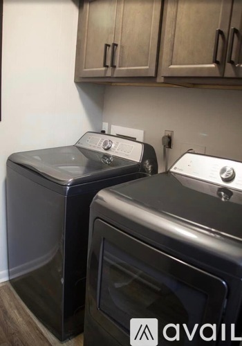 A black washing machine and dryer are in a kitchen.