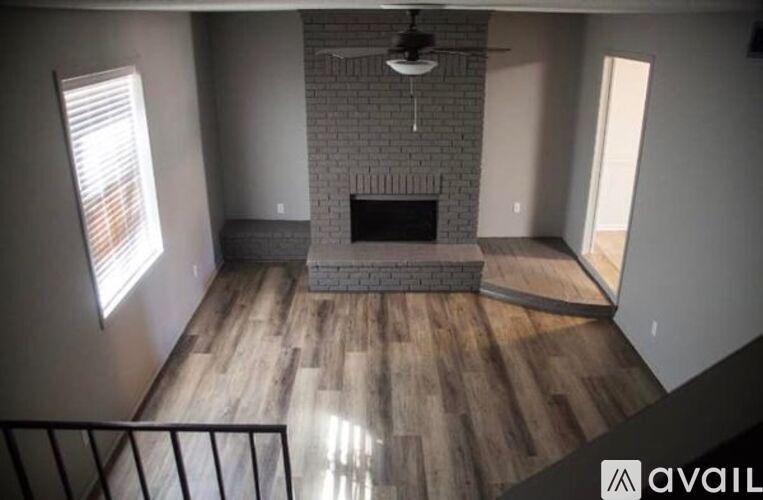 A living room with a brick fireplace and wooden floors.