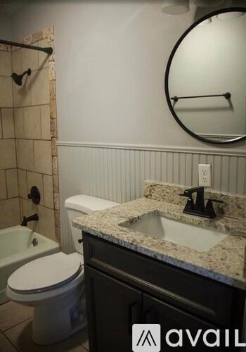 A bathroom with a toilet, sink, and mirror.