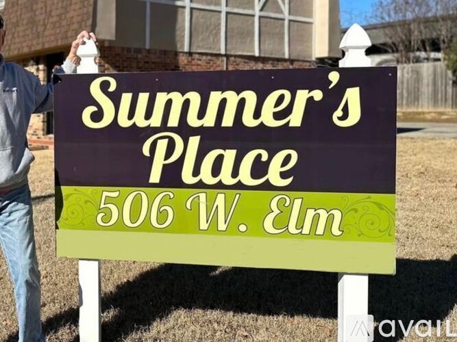 A man is holding a sign that says "Summer's Place" and "506 W. Elm".